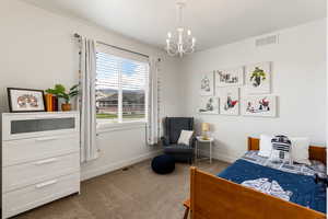 Bedroom featuring dark colored carpet and a chandelier