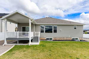Back of house featuring a wooden deck, a lawn, a shingled roof, and stucco siding