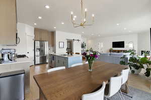 Dining area featuring a barn door, light wood-type flooring, and suspended lighting