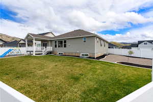 Rear view of house with a fenced backyard and a deck with mountain view