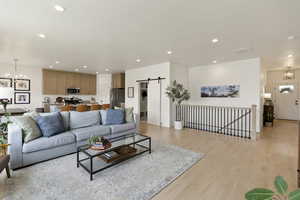 Living room featuring hanging lights, a barn door, and light wood-style flooring