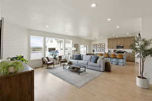 Living room with light wood-style floors and suspended lighting