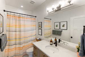 Bathroom with vanity, curtained shower, and recessed lighting
