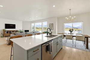 Kitchen with a kitchen breakfast bar, light wood finished floors, a center island with sink, stainless steel dishwasher, and plenty of natural light