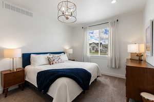 Bedroom with hanging lights and dark colored carpet