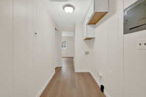 Hallway with light wood-style floors and wooden walls