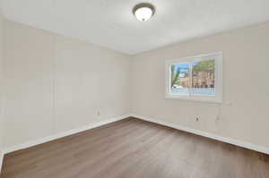 Unfurnished room with light wood-style floors and a textured ceiling
