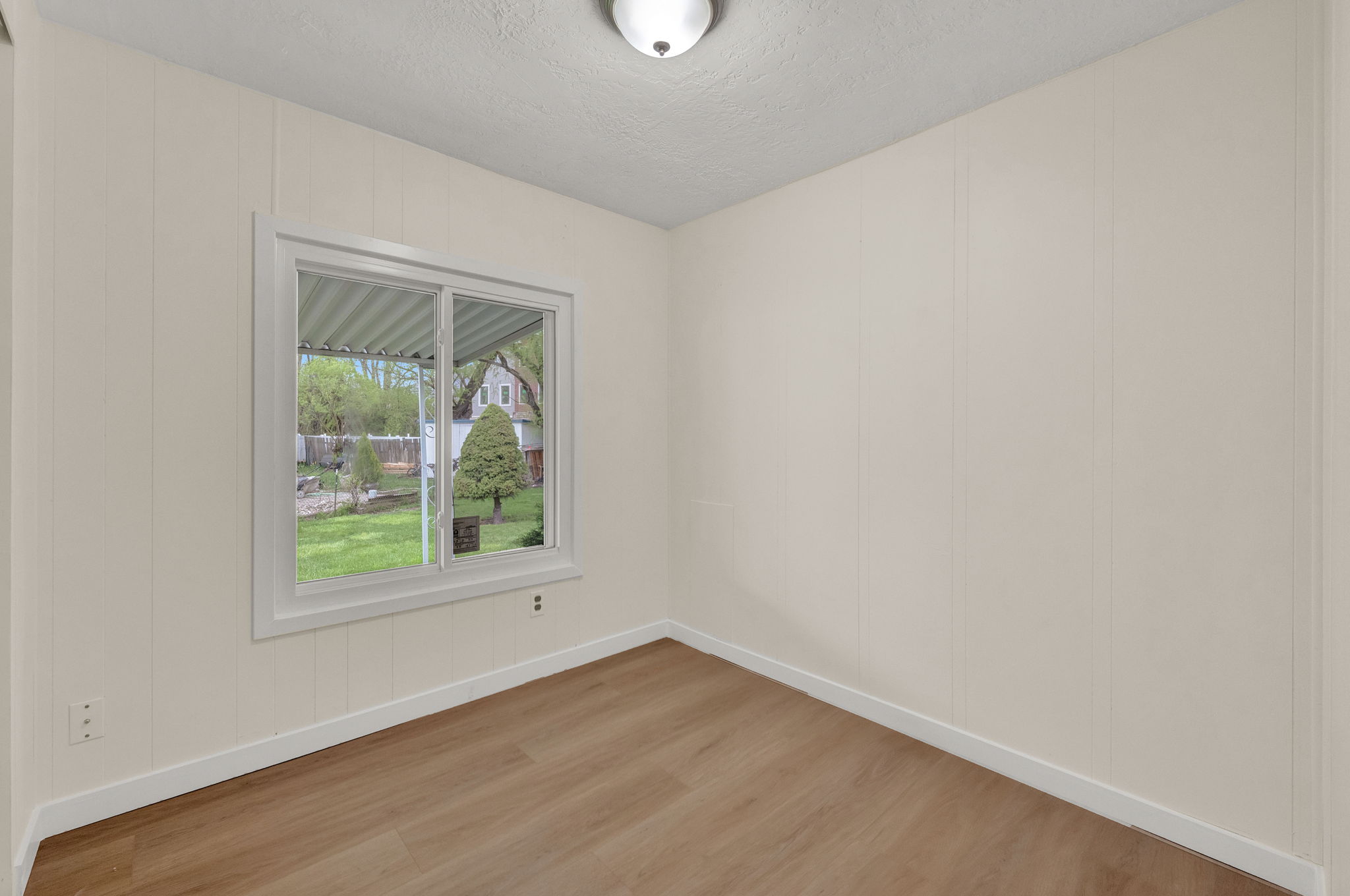 Spare room featuring light wood-type flooring, a textured ceiling, and a decorative wall
