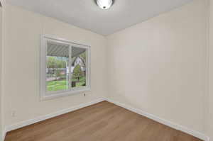 Spare room featuring light wood-type flooring, a textured ceiling, and a decorative wall