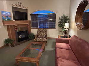 Living room featuring a fireplace with flush hearth and carpet