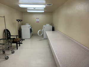 Communal laundry room featuring washing machine and clothes dryer