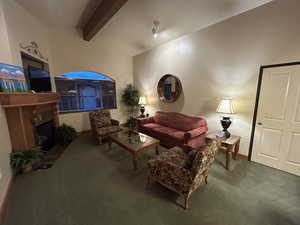 Living room featuring a fireplace, carpet, and vaulted ceiling with beams
