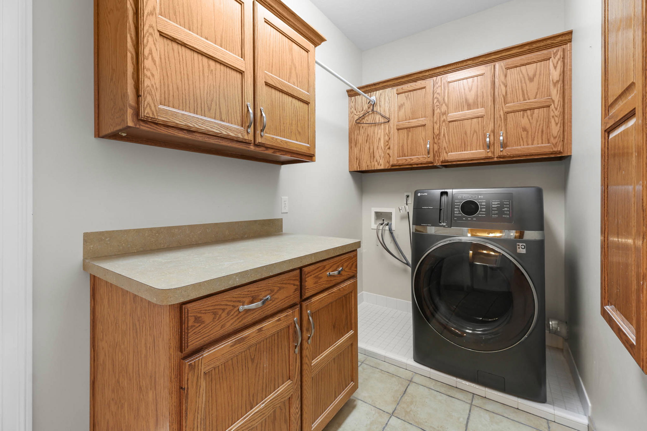 Laundry room featuring washer / dryer, cabinet space, and light tile patterned flooring