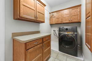 Laundry room featuring washer / dryer, cabinet space, and light tile patterned flooring