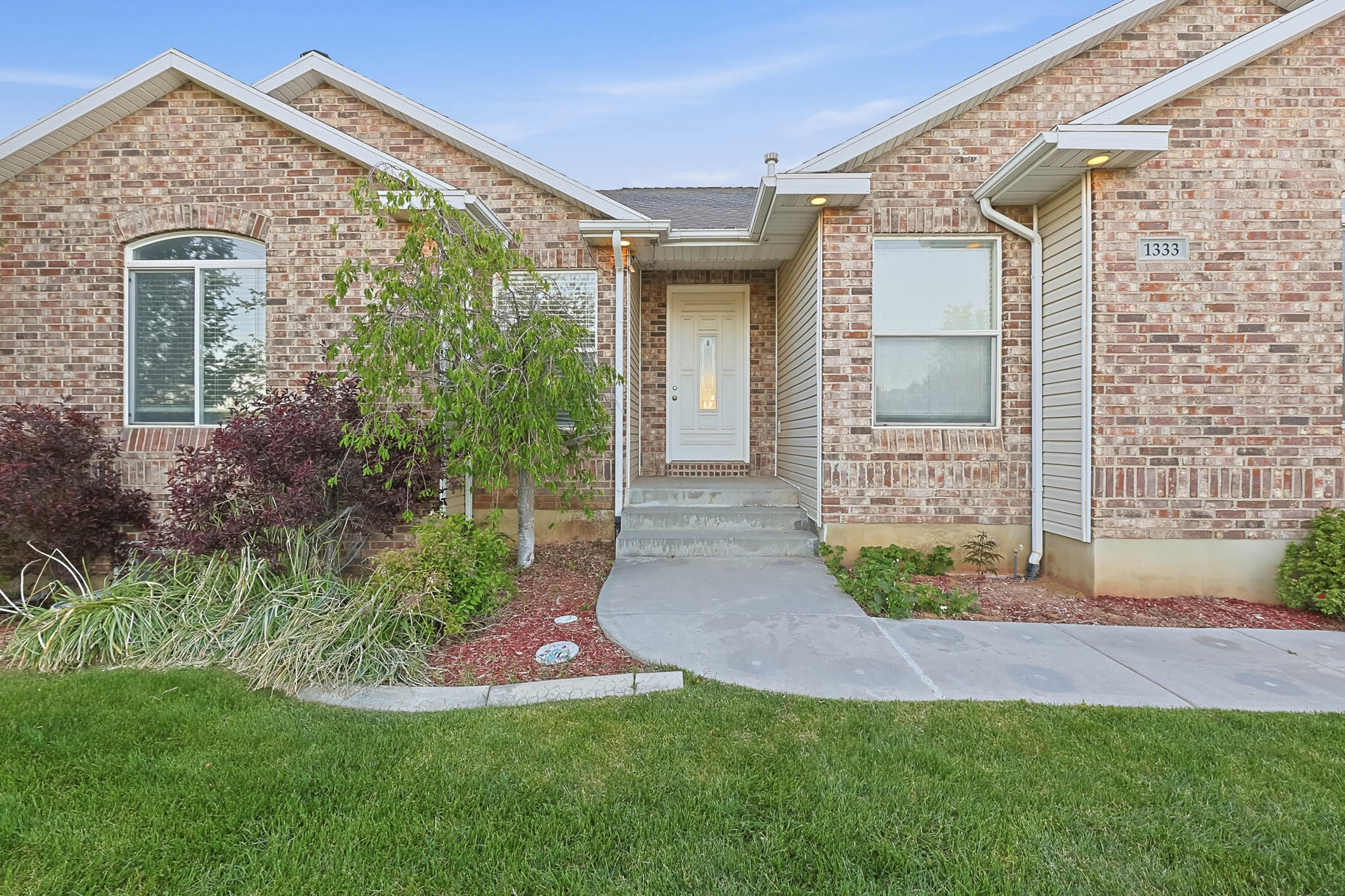 Doorway to property with brick siding and a yard