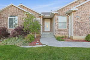 Doorway to property with brick siding and a yard