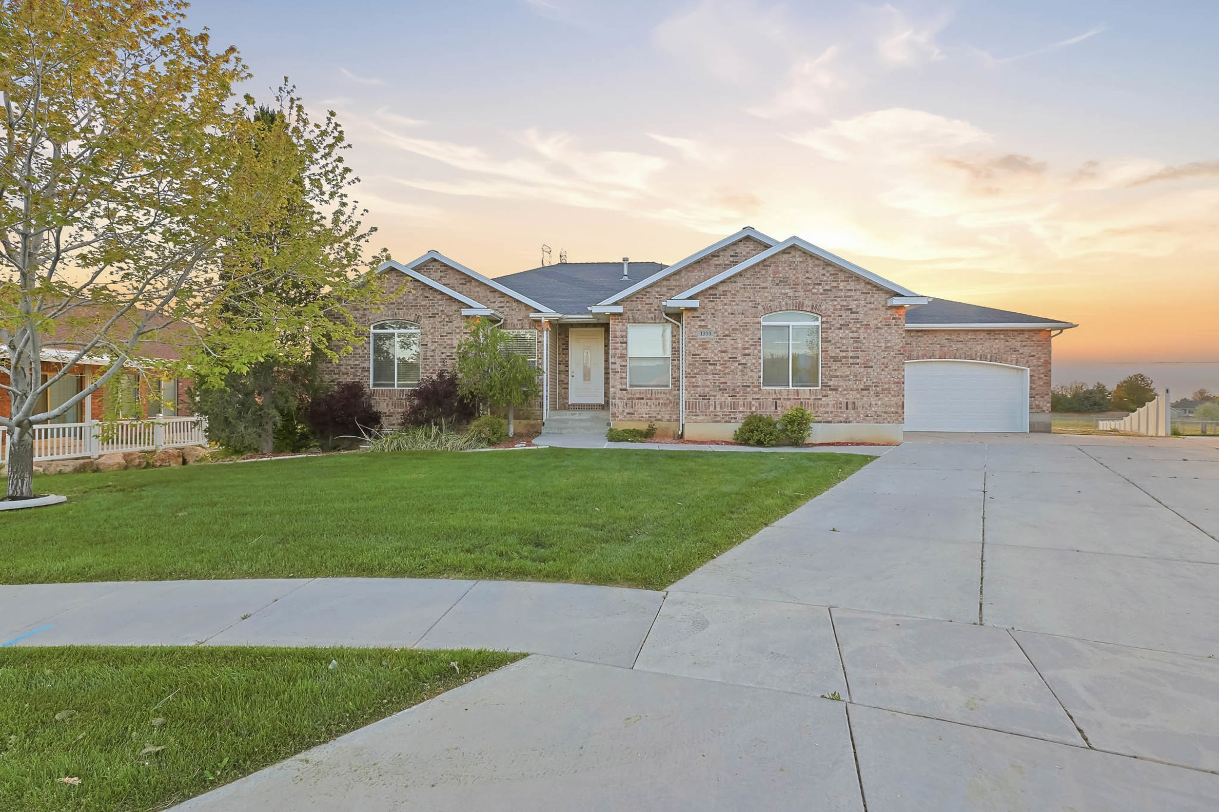 Ranch-style house featuring a front lawn, brick siding, concrete driveway, and an attached garage