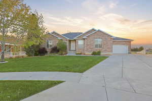 Ranch-style house featuring a front lawn, brick siding, concrete driveway, and an attached garage