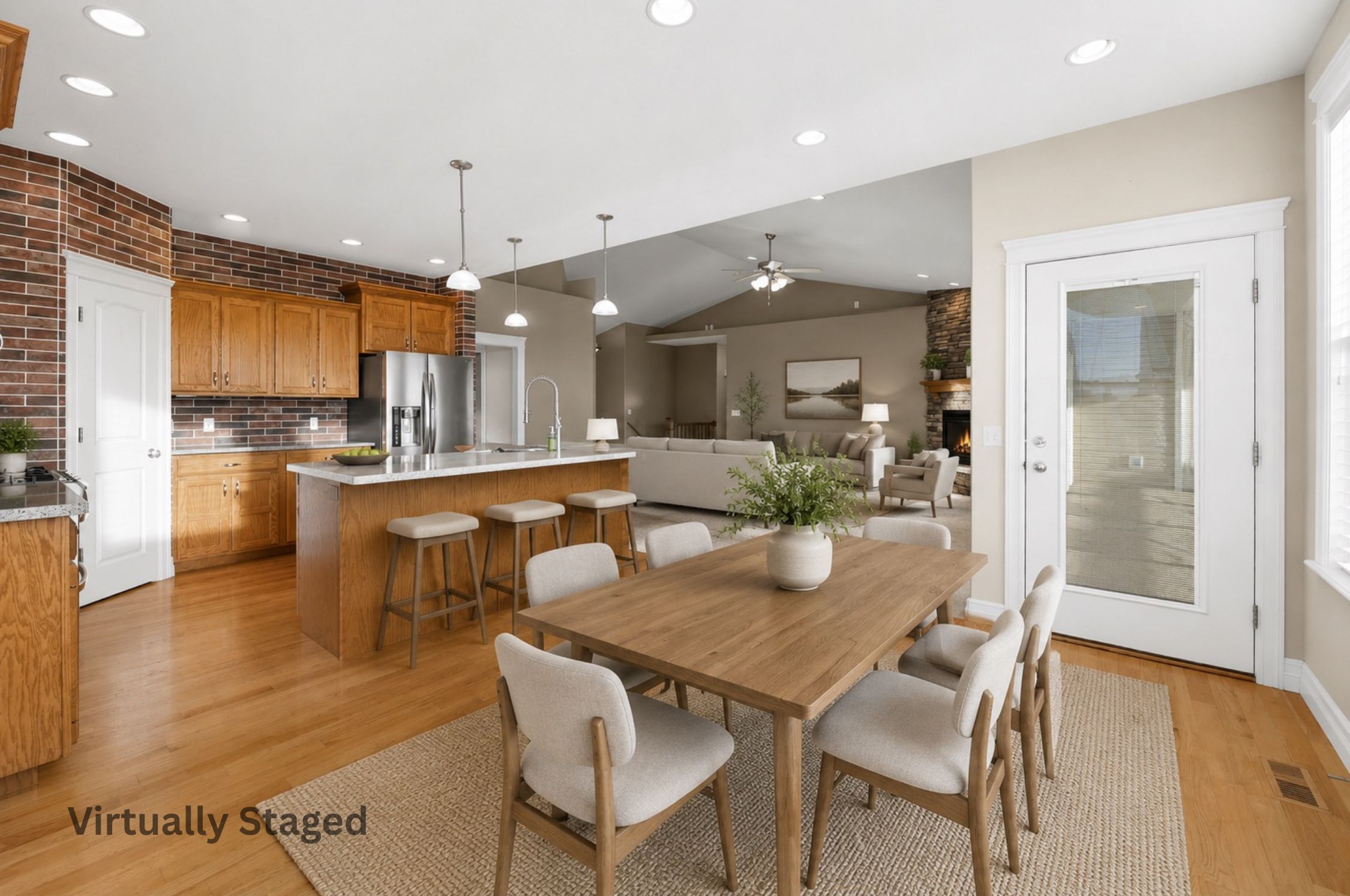 Open-concept kitchen and dining area featuring wood-finish flooring, brick accent wall, recessed lighting, and a kitchen island with pendant lighting. virtually staged