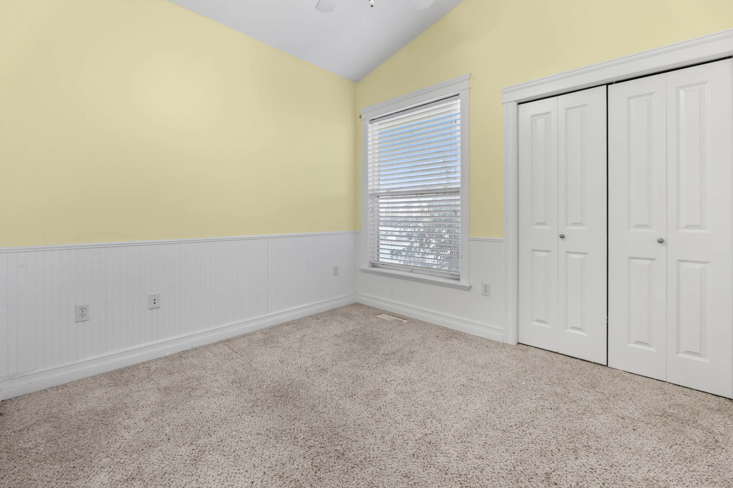 bedroom2  with a wainscoted wall, vaulted ceiling, a closet, and a ceiling fan