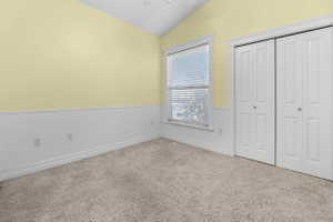 bedroom2  with a wainscoted wall, vaulted ceiling, a closet, and a ceiling fan