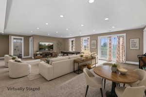Spacious entertainment room featuring recessed lighting, plush carpeting, multiple windows with white trim, and a sliding glass door providing external access. Walk out basement. Virtually staged