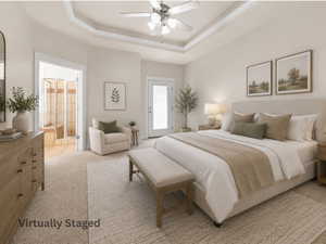 Carpeted primary  bedroom featuring a tray ceiling with a ceiling fan, a glass-paneled door, and an open doorway revealing a tiled shower with a built-in bench. virtually staged