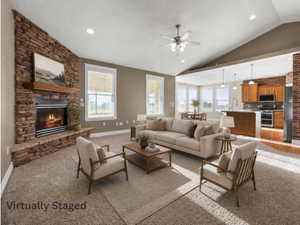 Living area featuring a stone fireplace with a wood mantel, vaulted ceiling with a ceiling fan, and recessed lighting. Virtually Staged