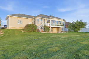 Rear view of property with a sunroom and a lawn