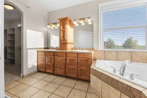 Dual vanity primary ensuite bath  with wood cabinetry and countertop, featuring dual sinks and an integrated tall storage cabinet