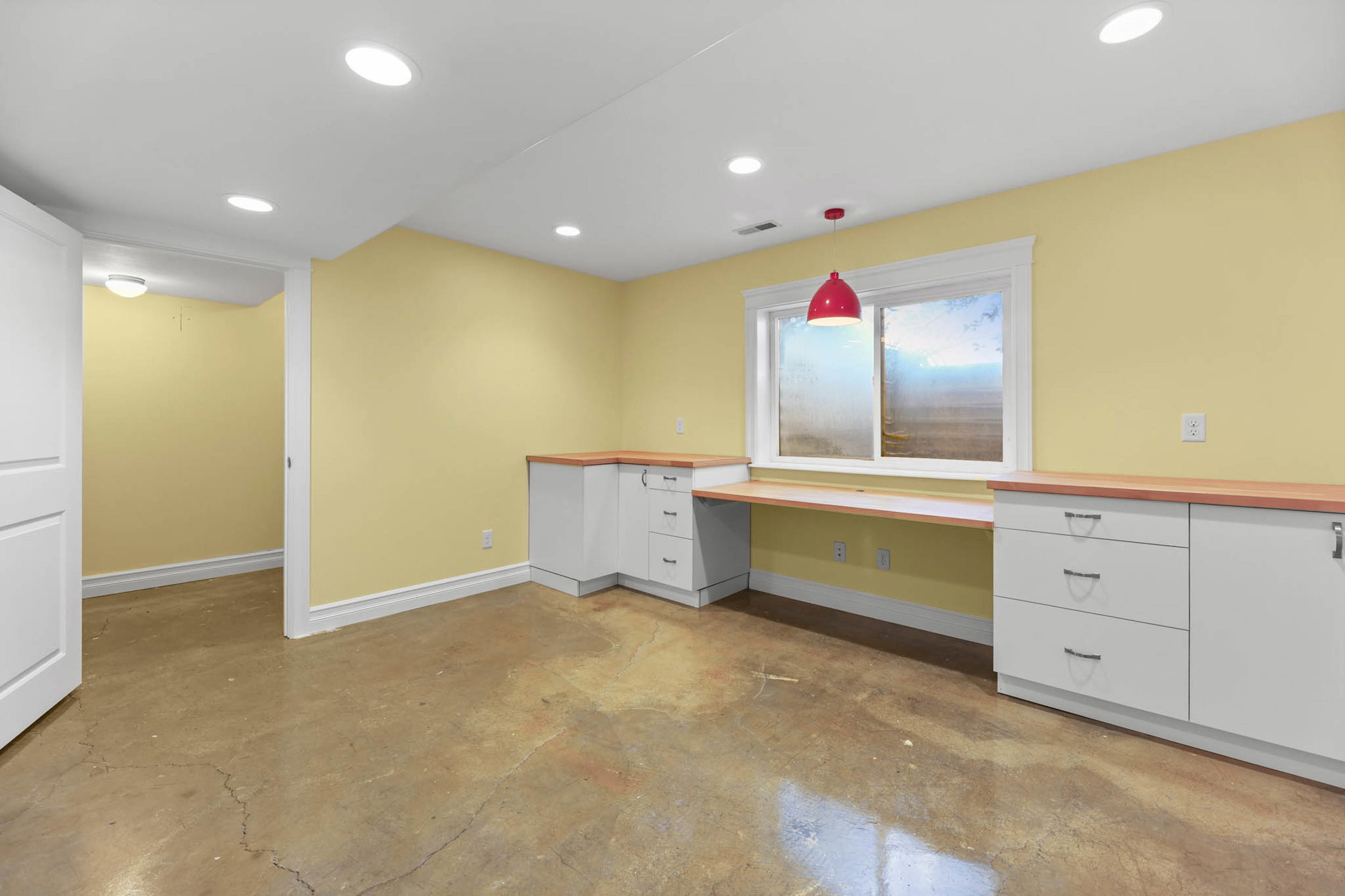 Bedroom/craft room/office with built in study area, white cabinetry, concrete flooring, and wooden counters. Huge closet