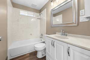 Bathroom with vanity, bathing tub / shower combination, and dark wood-style floors