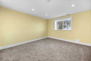 Carpeted spare room with baseboards and recessed lighting