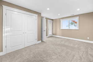 Unfurnished bedroom featuring light colored carpet, a closet, and recessed lighting. external access