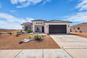 View of front of house with an attached garage, stucco siding, driveway, and a tiled roof