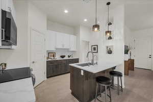 Dual tone kitchen with dual tone cabinets, a kitchen bar, light stone countertops, hanging light fixtures, and a peninsula
