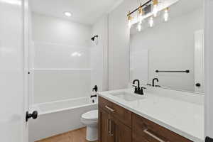 Bathroom featuring vanity, light wood-style floors, and shower / washtub combination