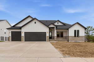 Modern farmhouse style home with board and batten siding, a garage, stone siding, driveway, and roof with shingles