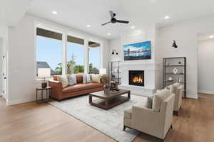 Living area with a large fireplace, a ceiling fan, light wood-style floors, and recessed lighting