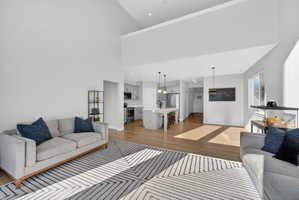 Living area featuring light wood-style floors, a high ceiling, and recessed lighting