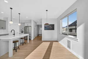Kitchen featuring gray cabinets, freestanding refrigerator, a kitchen bar, and light wood finished floors
