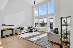 Living room featuring a ceiling fan, light wood-type flooring, and lofted ceiling