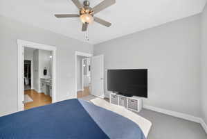 Bedroom with ensuite bath, a ceiling fan, and light colored carpet