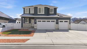 View of front of property featuring concrete driveway, stone siding, stucco siding, a porch, and a mountain view