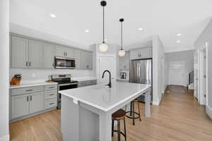 Kitchen with gray cabinetry, stainless steel appliances, a breakfast bar area, and pendant lighting