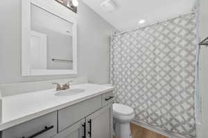Bathroom with curtained shower, vanity, and wood finished floors