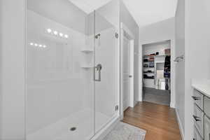 Bathroom featuring vanity, a walk in closet, a stall shower, and light wood-style flooring