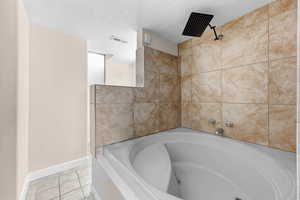 Full bath featuring a textured ceiling, a bath, and light tile patterned flooring