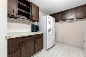 Kitchen featuring dark wood finish cabinetry, light flooring, and open shelves