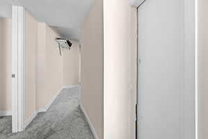 Hall with light carpet and a textured ceiling